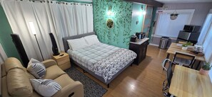 Une chambre comprenant un lit, des tables de chevet, un canapé, un bureau et un coin cuisine.
