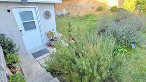 A house with a white door, a small garden with various plants, and a welcome mat.