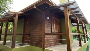 A wooden cabin with a balcony, a green exterior wall, and a small window. - Stillo Gramado Dutra (Gramado)