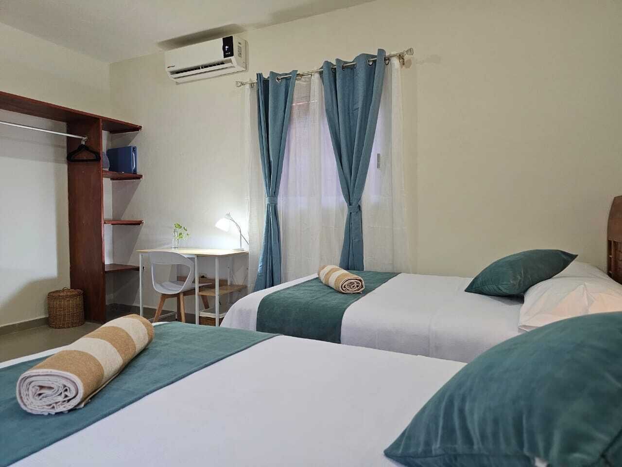 A hotel room with two beds, a desk, and a chair.