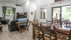 Amplia sala de estar con mesa de comedor, asientos cómodos, televisor de pantalla plana y ventilador de techo.