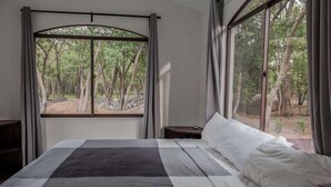 Un dormitorio con una cama grande, una mesita de noche y una ventana con cortinas.