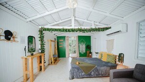 A room with a bed, a sofa, a wooden table, and a mirror.