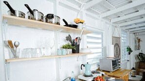 A kitchen with a wooden countertop, stainless steel sink, and various kitchen utensils and appliances.