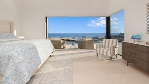 Ein Schlafzimmer mit einem großen Bett, einer Sitzecke mit Meerblick und einer Kommode.
