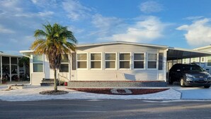 A single-story house with a covered garage, a palm tree in the front yard, and a driveway leading to the garage. - Snow Bird Alert -3 Month Rental - Venice Isle Estates -2 Bed 2 Bath House  (Venice)