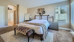 A bedroom with a bed, bedside tables, a bench, a ceiling fan, and a wall decoration. - Cactus Bloom - Cozy Desert Retreat in Chandler (Chandler)