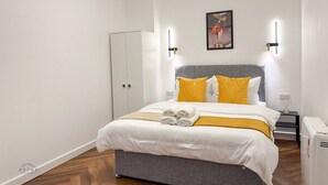 Ein Schlafzimmer mit Bett, Kleiderschrank, Nachttisch und einer Wandleuchte.