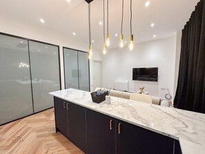 A modern kitchen with a marble countertop, black cabinets, and pendant lighting. - Modern 2 Bedroom Flat in Luton Town Centre (Luton)