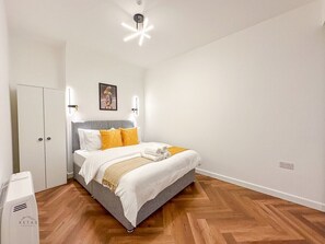 Quarto com cama, guarda-roupa e luminária no teto.