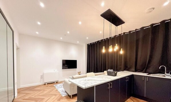 A modern kitchen with a marble countertop, black cabinets, and a black curtain. - Modern 2 Bedroom Flat in Luton Town Centre (Luton)