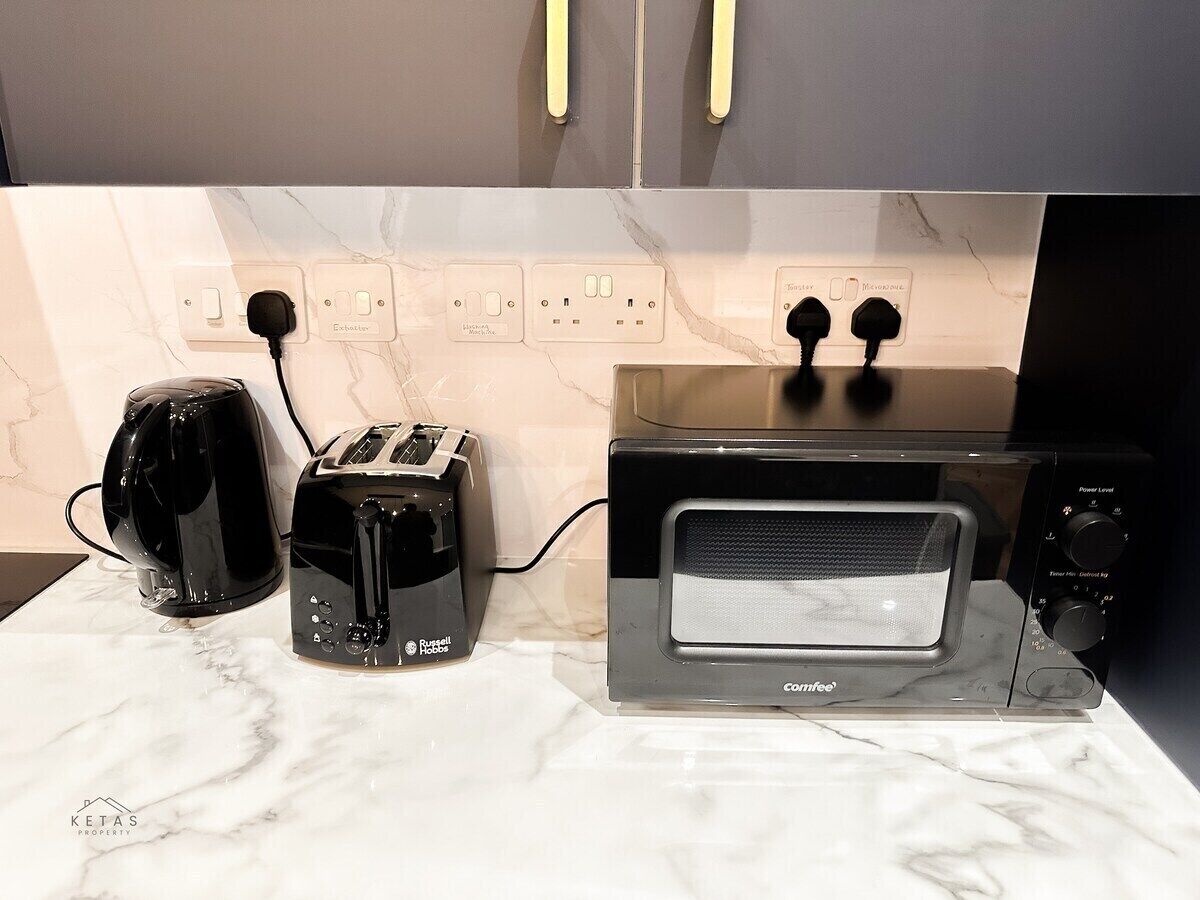 A kitchen with a countertop, a toaster, a kettle, and a microwave.