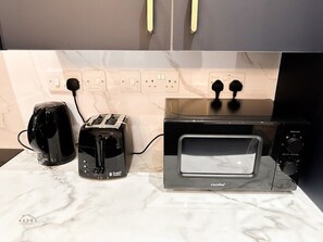 A kitchen with a countertop, a toaster, a kettle, and a microwave. - Modern 2 Bedroom Flat in Luton Town Centre (Luton)