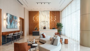 Un moderno vestíbulo de hotel con un mostrador de recepción, una zona de estar y un amplio ventanal.