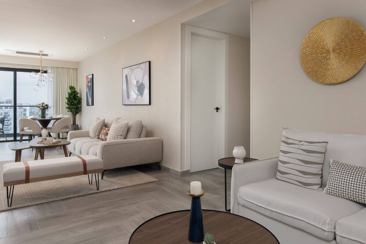 Una sala de estar moderna con un sofá, un banco, una mesa de centro y un comedor con una mesa y sillas.