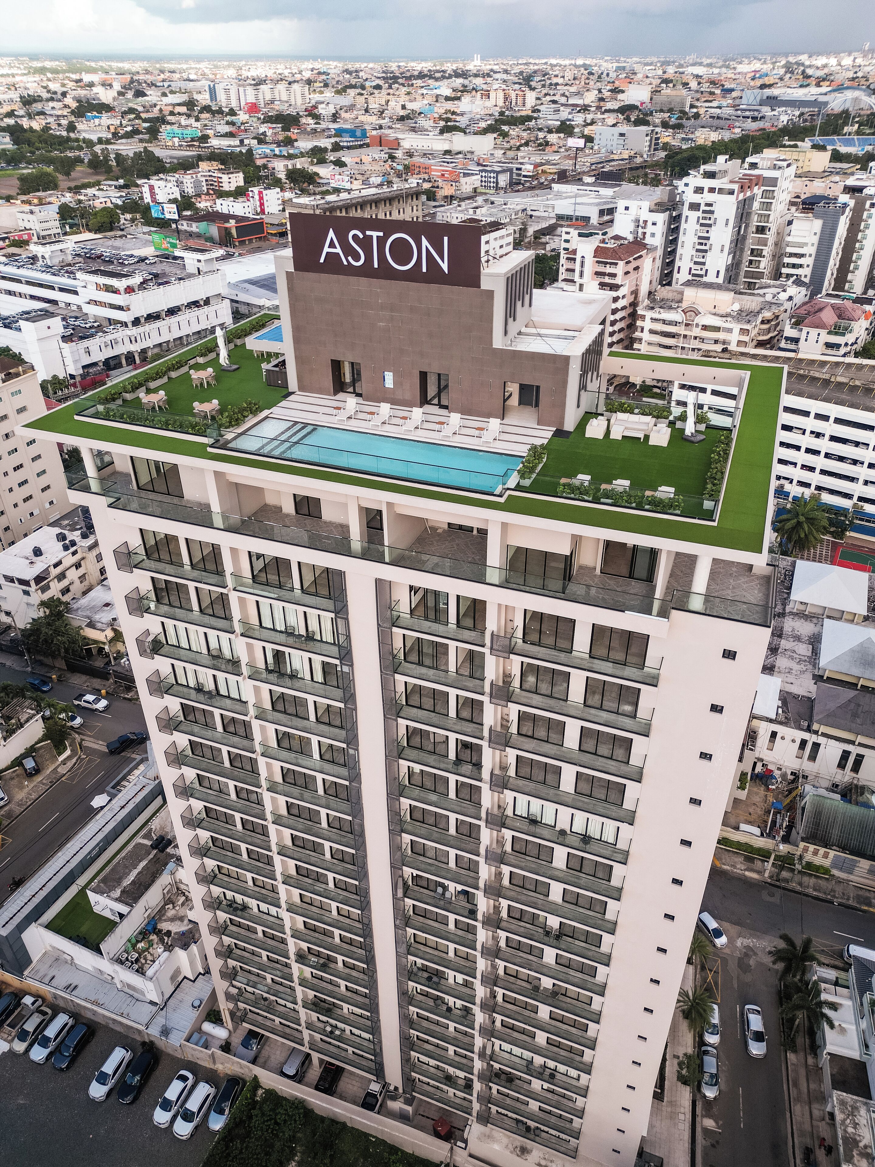A high-rise building with a rooftop pool and a sign reading "ASTON".