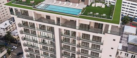 A high-rise building with a rooftop pool and a sign reading "ASTON".