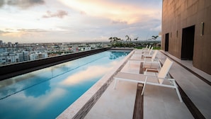 Piscina en la azotea con sillas de descanso y vista panorámica de la ciudad.