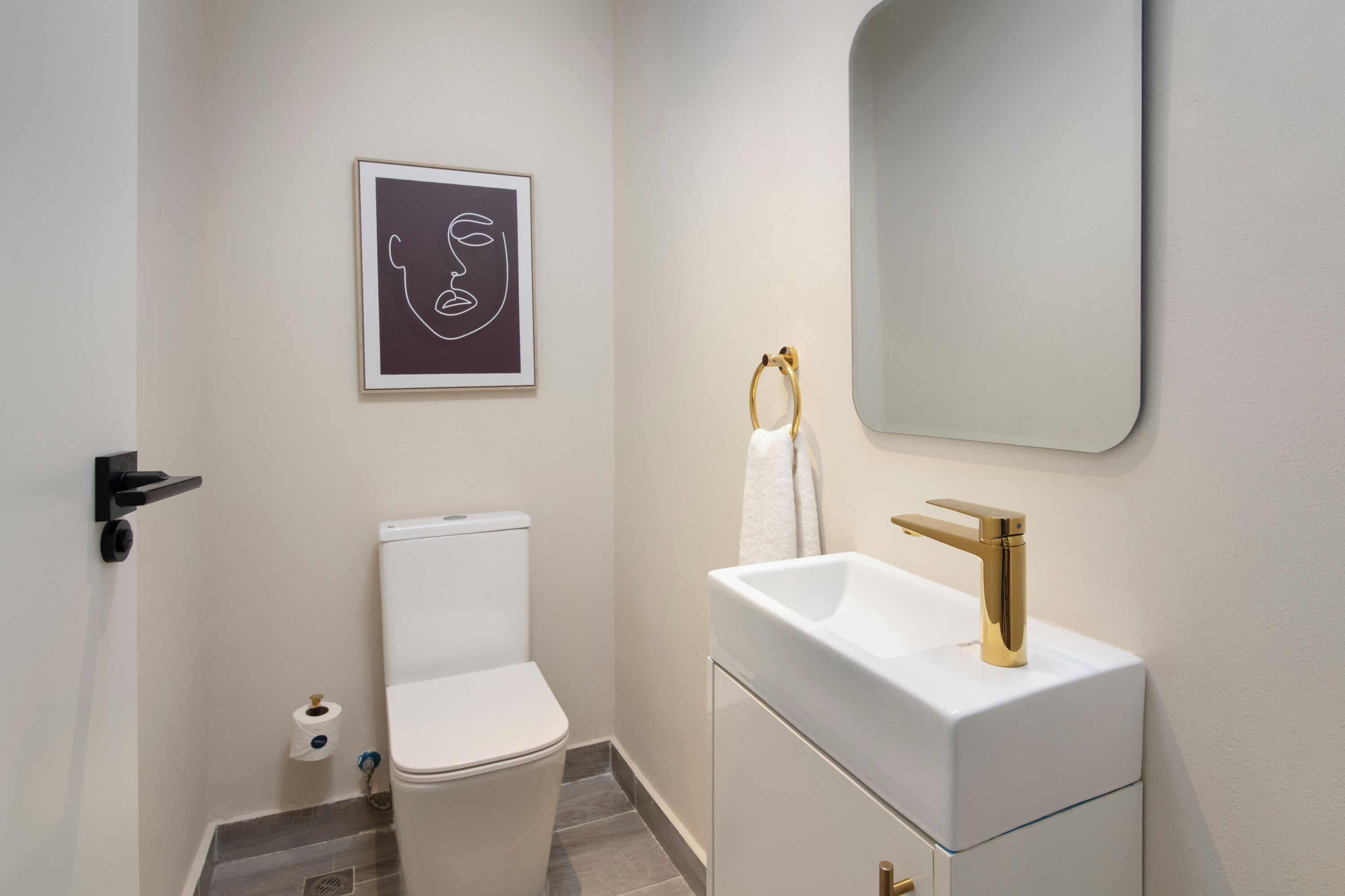 Un baño moderno con inodoro, lavamanos y espejo.