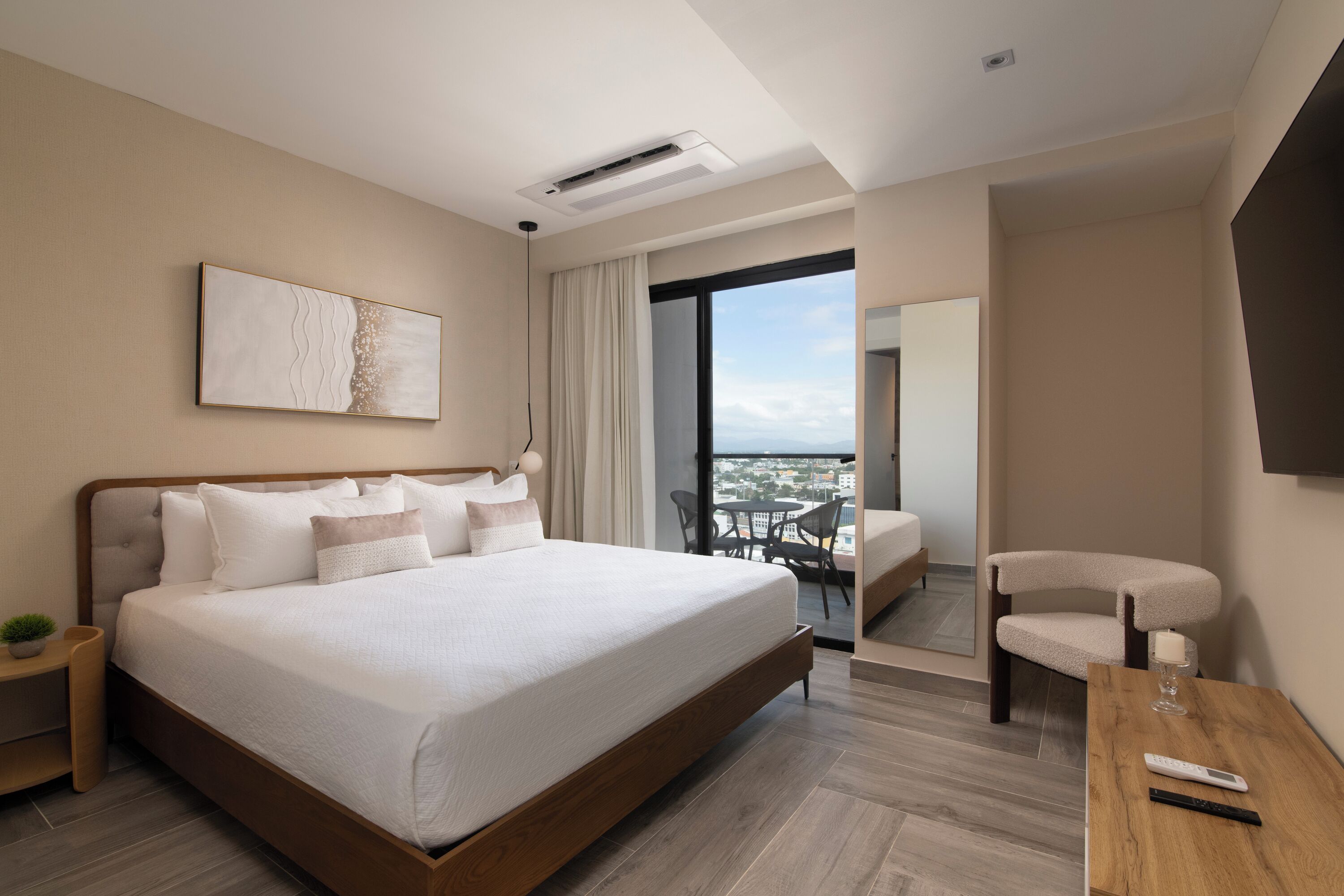 Una habitación de hotel moderna con una cama grande, una mesita, una silla y vistas a la ciudad.