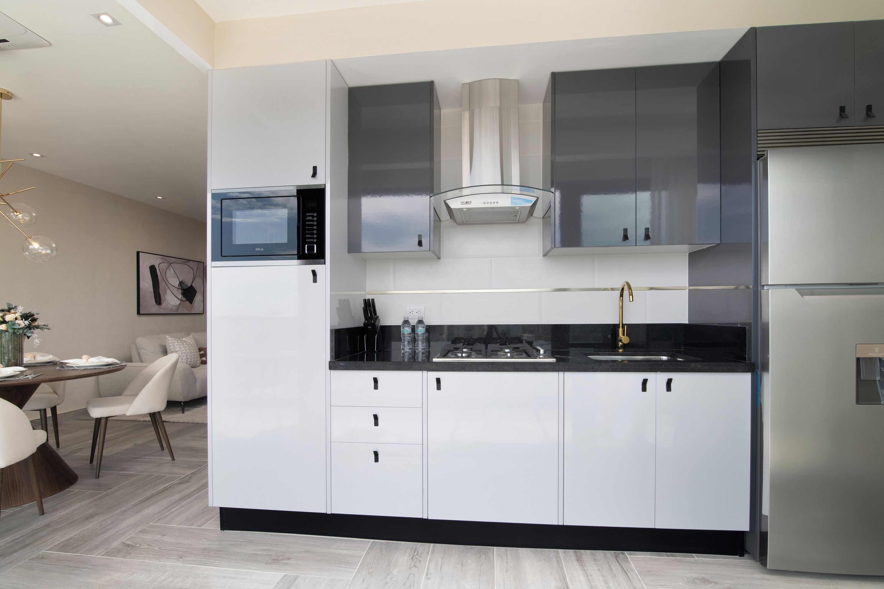 Une cuisine moderne avec des meubles blancs, un réfrigérateur en acier inoxydable, un four à micro-ondes et une cuisinière à gaz.