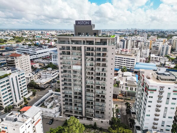 A high-rise building with a prominent 'Aston' sign on top, surrounded by other residential buildings.