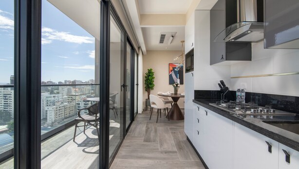 Una cocina moderna con un ventanal grande, un comedor con sillas y vistas a la ciudad.