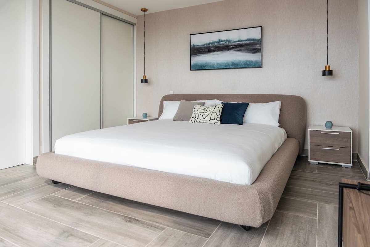 Un dormitorio moderno con una cama grande, mesitas de noche y una obra de arte colgada en la pared.