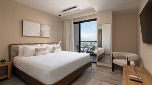 Una habitación de hotel moderna con una cama grande, una mesita, una silla y vistas a la ciudad.