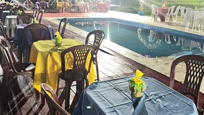 An outdoor dining area with tables and chairs, a pool, and a stage with lighting. - Pedro Alexandre Da Costa (Presidente Figueiredo)