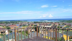 A residential area with houses, a wooden deck, and a view of the ocean.