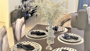 A dining area with a table set for four, a vase with flowers, and a mounted television.