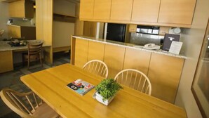 A compact kitchen with wooden cabinets and a dining area with a wooden table and chairs. - Prime ski week studio in enchanting Snowbird (snowbird)