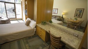 A compact hotel room with a bed, a small desk, a chair, a dining table, and a large window. - Prime ski week studio in enchanting Snowbird (snowbird)