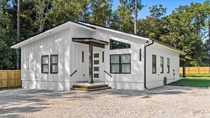 A single-story mobile home with a white exterior, a front entrance with a set of steps, and a small porch area. - Modern, Cozy and Spacious Home in Foley Alabama. (Foley)