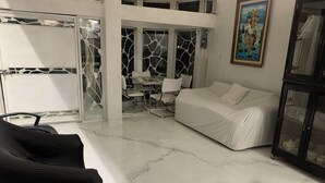 Una sala de estar moderna con un sofá blanco, un sillón negro y una mesa de vidrio.