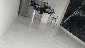 Una habitación con piso blanco brillante, una zona de cocina con encimera de mármol y una pared de acento en mármol negro.