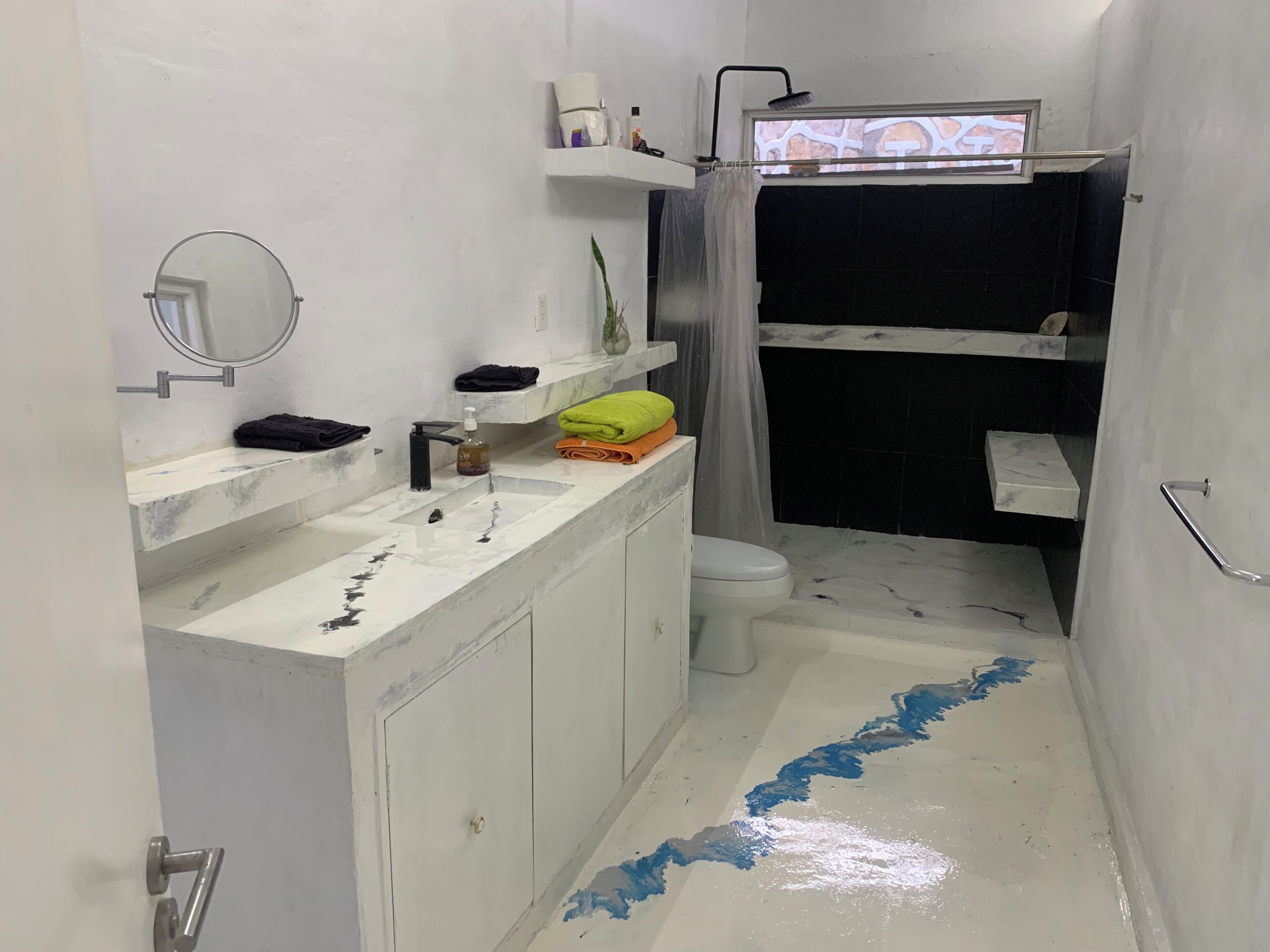 A bathroom with a white sink, mirror, and toilet. There are towels and toiletries on the counter.