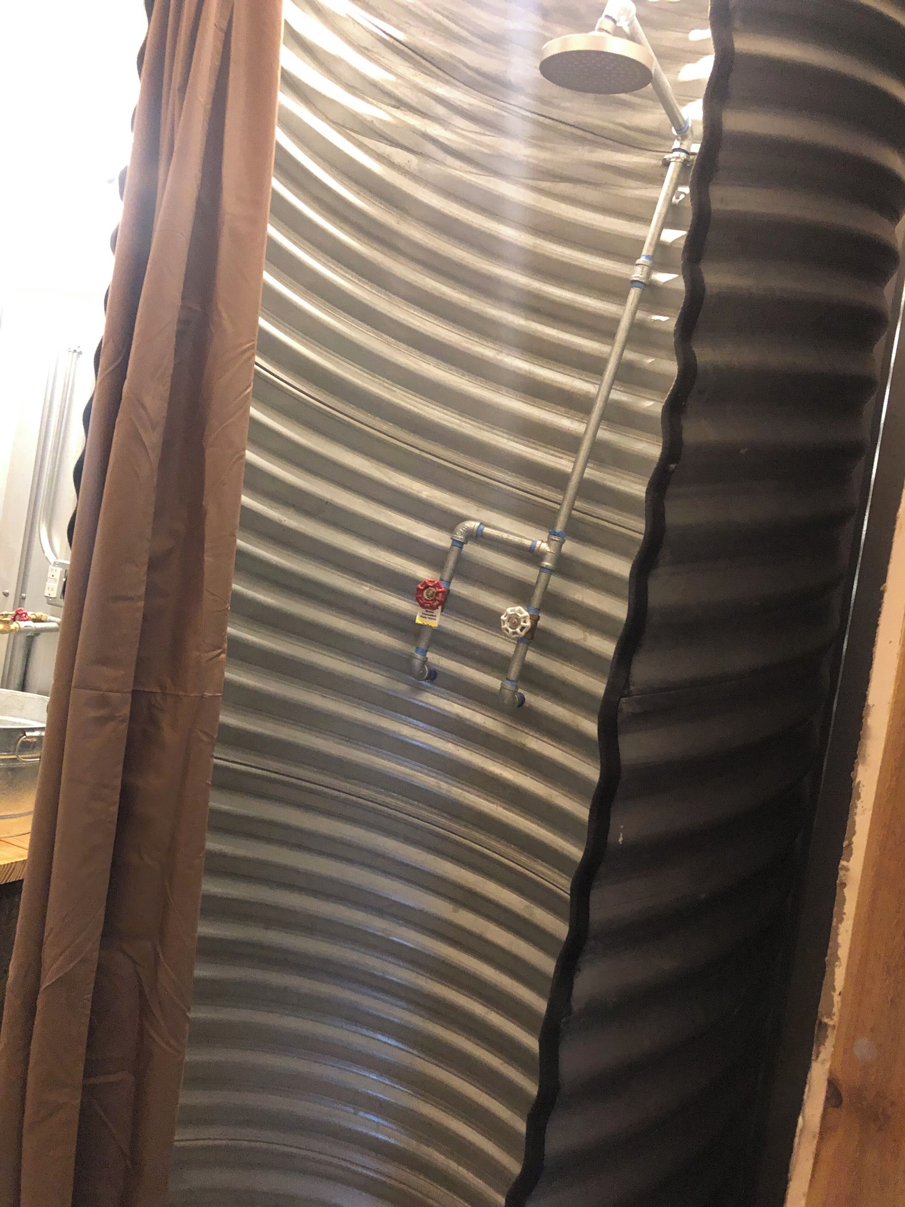 A shower with a curved ceiling and a handheld showerhead.
