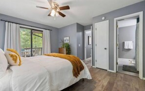 Relax in this serene bedroom with a large bed, ceiling fan, and a view of the outdoors through the window.