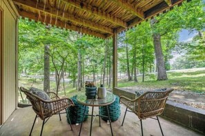 Relax in a serene outdoor setting surrounded by lush greenery, with a comfortable seating area under a pergola.