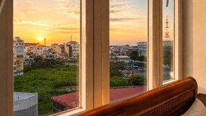 A room with a large window overlooking a cityscape at sunset.