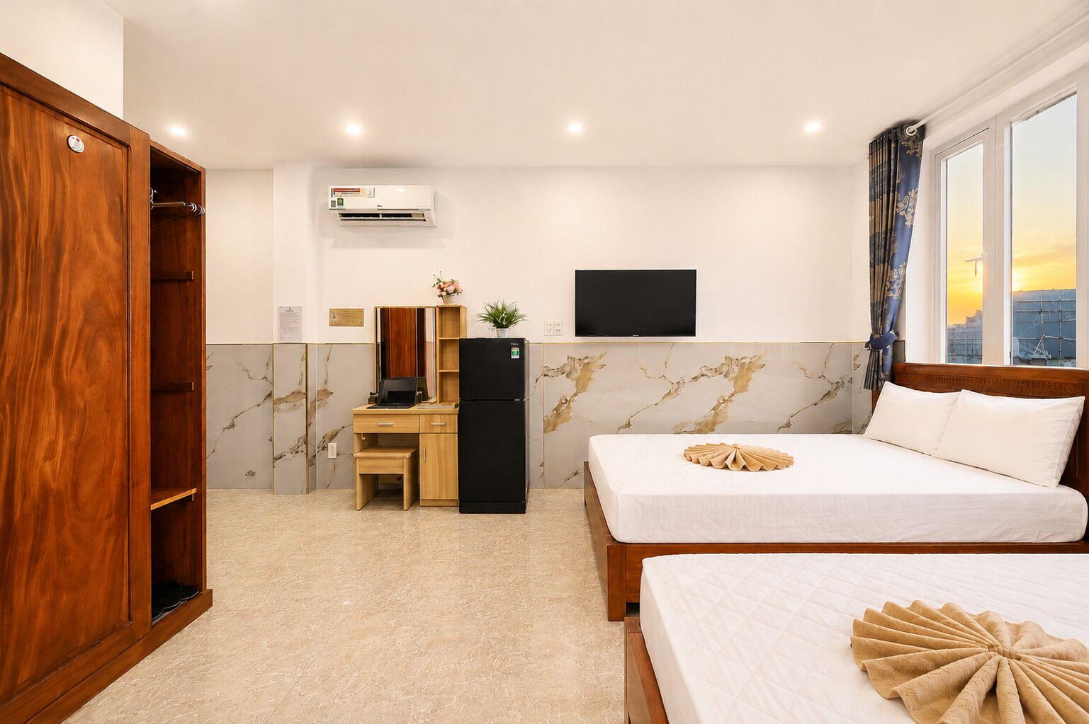 A hotel room with a bed, a desk, a wardrobe, a TV, and a city view.