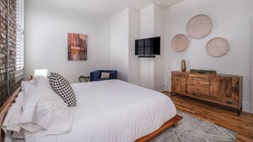 Una camera da letto con un letto, una televisione, un comò e piatti decorativi appesi al muro.
