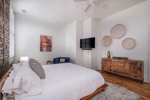 A bedroom with a bed, a television, a dresser, and decorative plates on the wall. - Modern Stylish & Spacious Loft w/Indoor Parking (Birmingham)