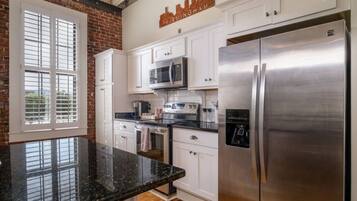A kitchen with white cabinets, a stainless steel refrigerator, a microwave, and a toaster.