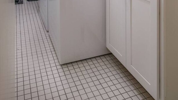 Une buanderie avec un mur en briques, des armoires blanches et un lave-linge.