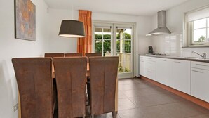 Een moderne keuken met witte kasten, een roestvrijstalen spoelbak en een groot raam.