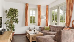 Een woonkamer met een bank, salontafel en een plant in pot.