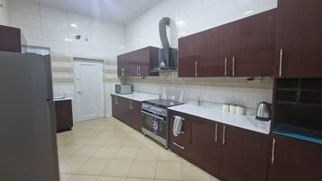 A kitchen with dark brown cabinets, a white countertop, a stainless steel oven, and a refrigerator.